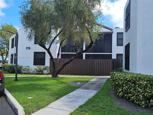 a view of a backyard with potted plants and large tree