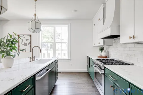 a kitchen with granite countertop a sink stainless steel appliances and white cabinets