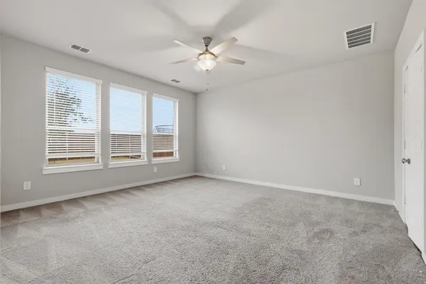 an empty room with windows and ceiling fan