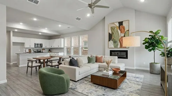 a living room with furniture potted plant and kitchen view