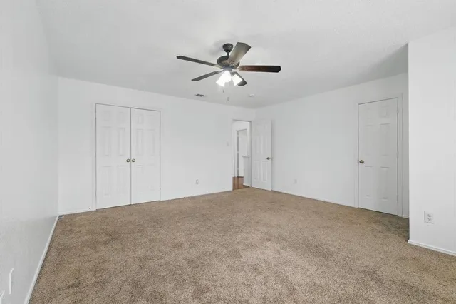 an empty room with a window and a ceiling fan
