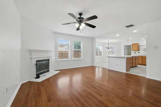 a view of an empty room with wooden floor and a fireplace