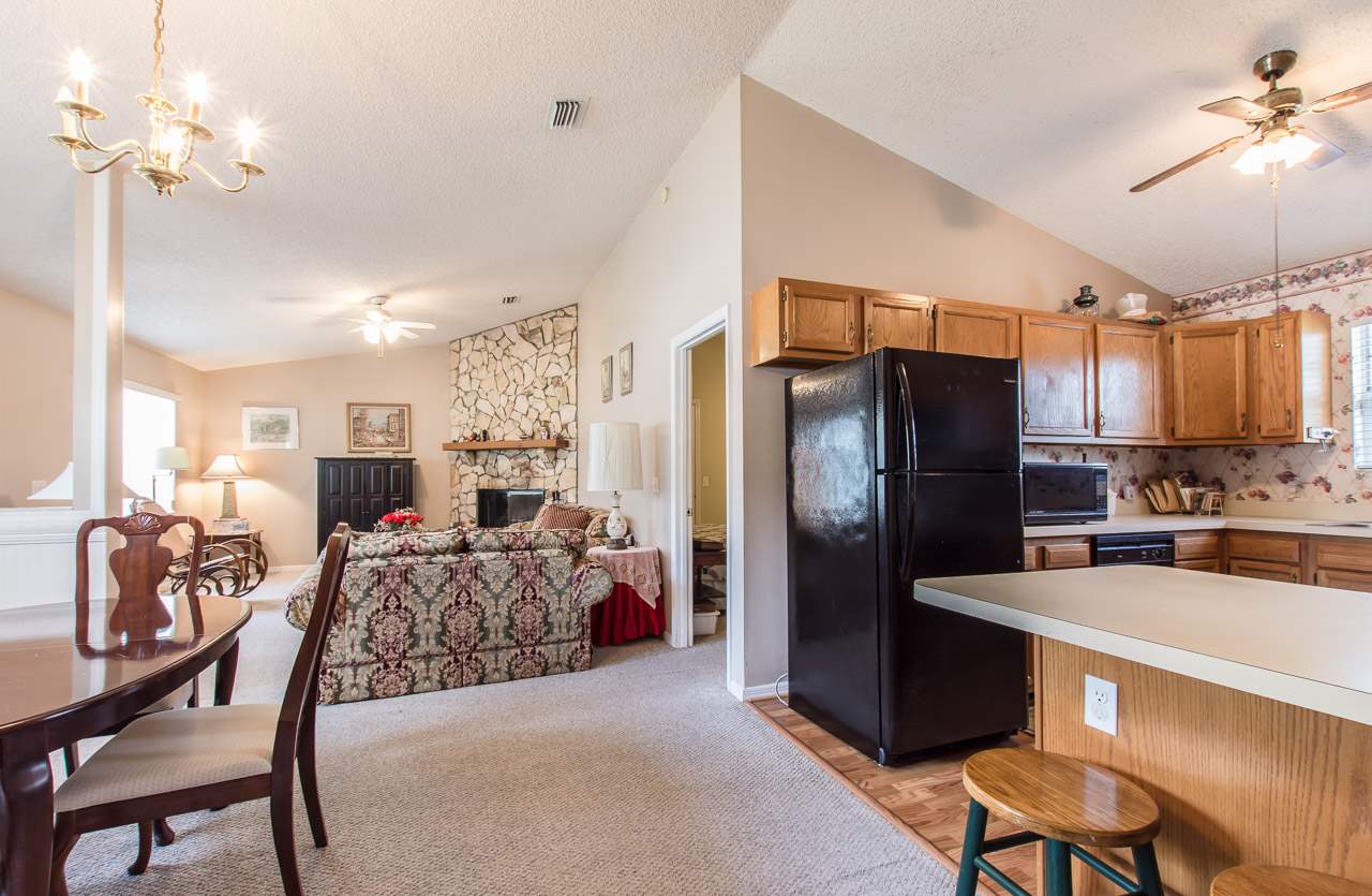 174 Segovia Road St. Augustine, FL 32086 - Photo 7 of 40 a kitchen with stainless steel appliances kitchen island granite countertop a refrigerator a stove a sink dishwasher a dining table and chairs with wooden floor