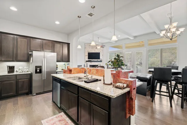 a kitchen with a refrigerator a stove a dining table and chairs with wooden floor