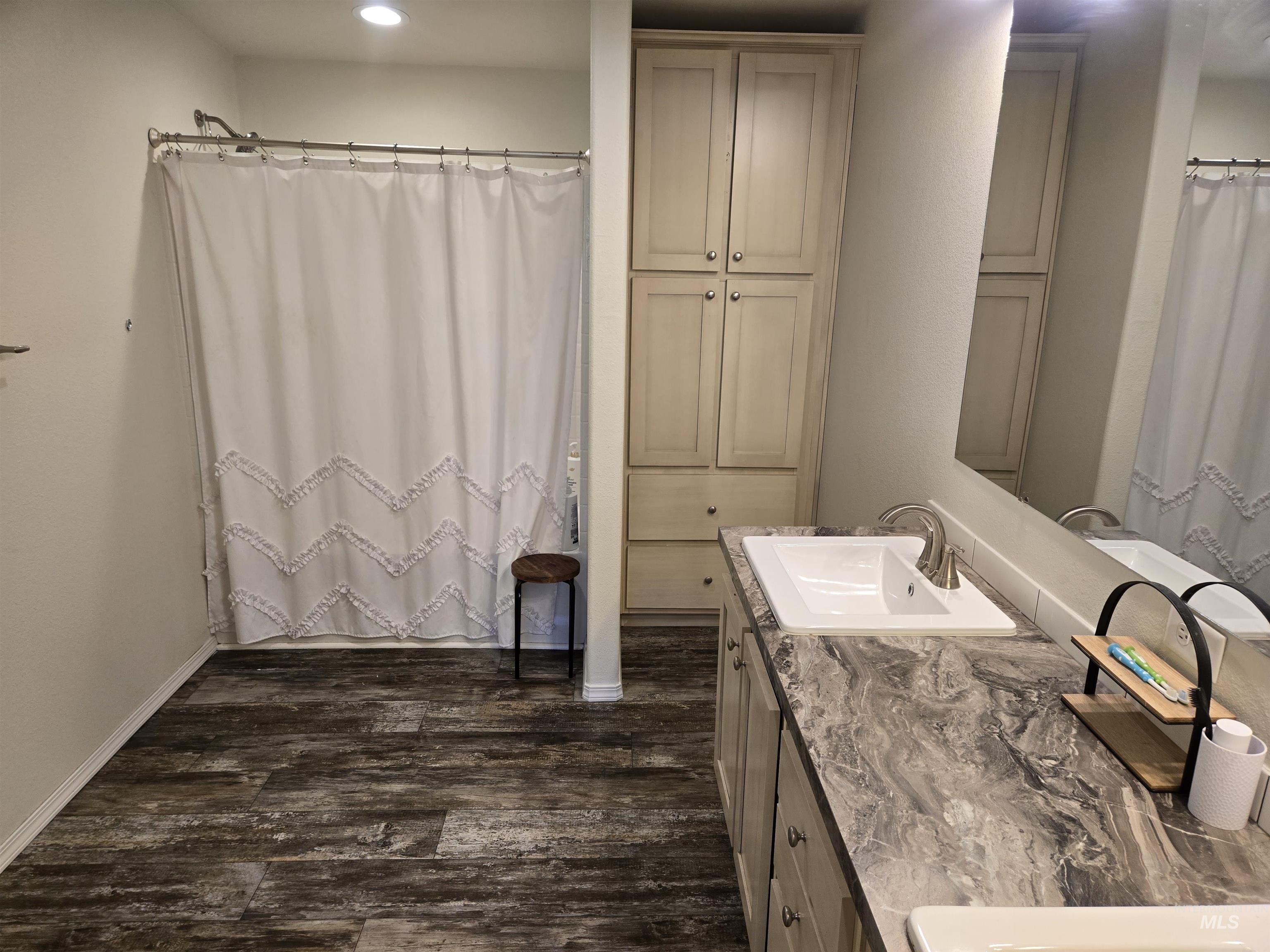 174 Konkolville Road Orofino, ID 83544 - Photo 18 of 43 Bathroom featuring a double vanity with integrated sinks, a built-in storage cabinet, and wood-finish flooring