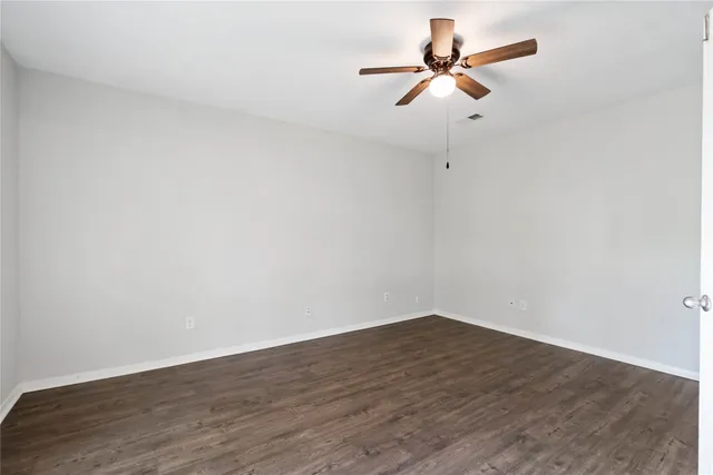 a view of a room with wooden floor a ceiling fan and window
