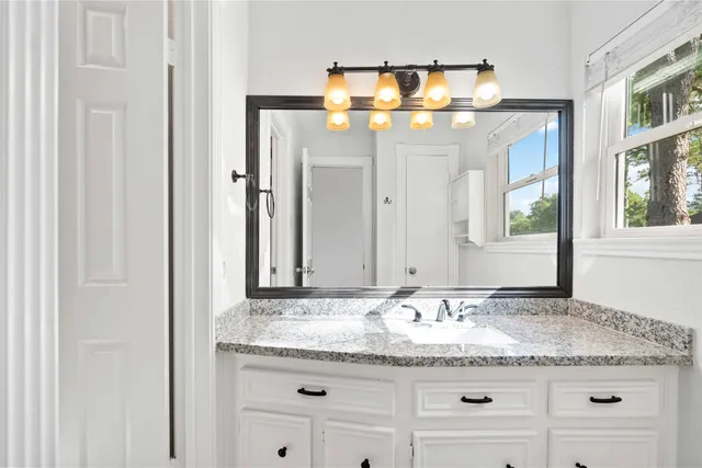a bathroom with a granite countertop sink and a mirror