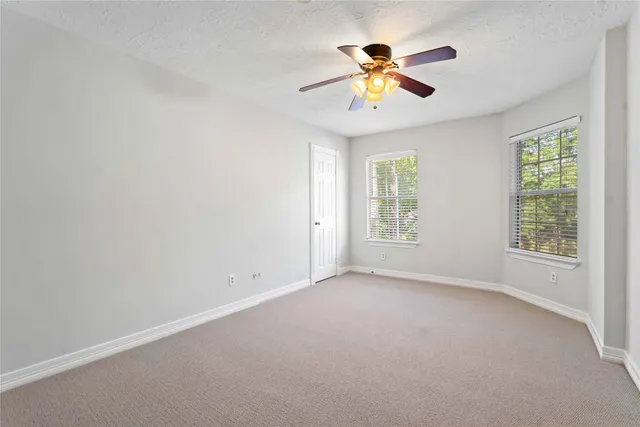 an empty room with window and a ceiling fan