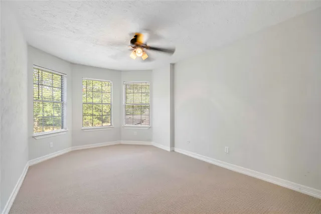 an empty room with windows and fan