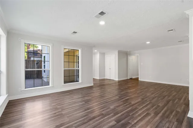 a view of an empty room with wooden floor and windows