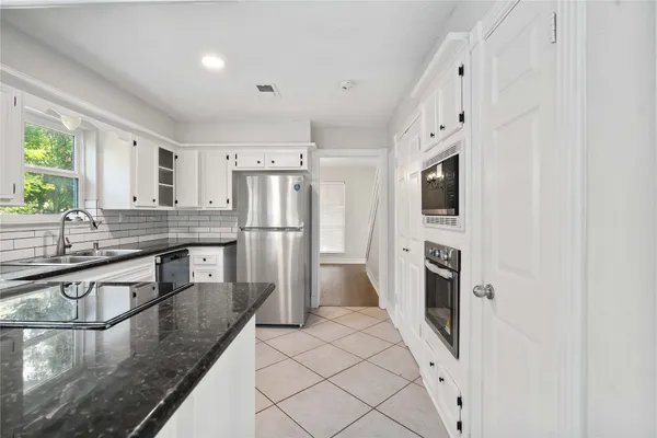 a kitchen with granite countertop white cabinets sink and window