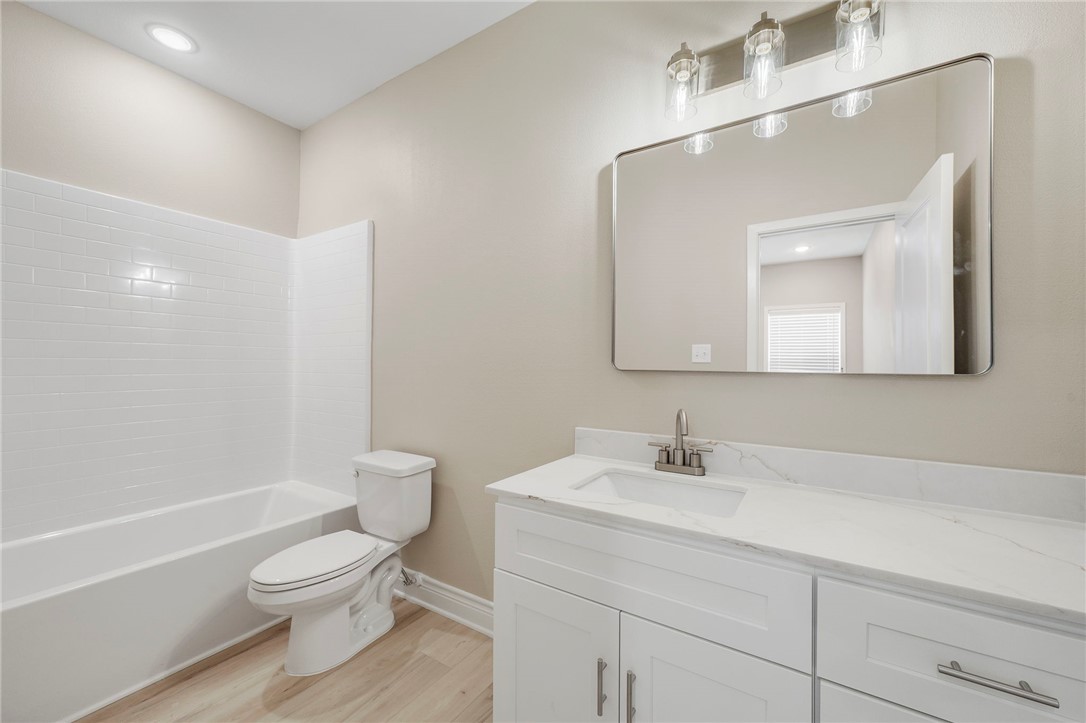 3213 Link Street, Unit 112 Bryan, TX 77801 - Photo 11 of 25 a bathroom with a toilet a sink a mirror and a bathtub