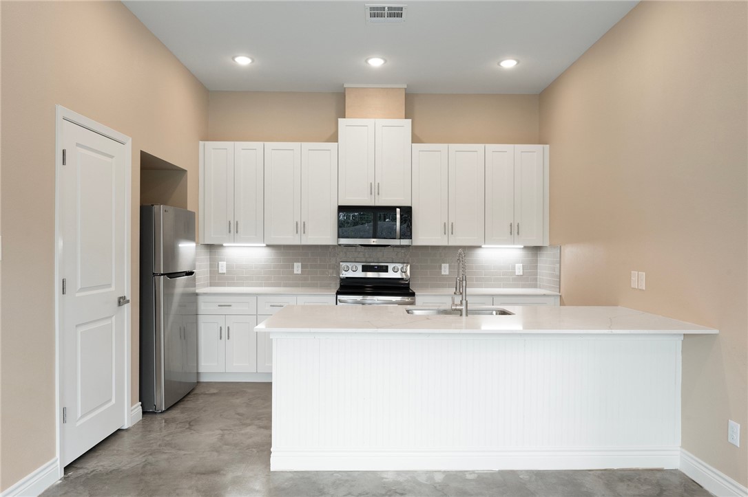 3213 Link Street, Unit 112 Bryan, TX 77801 - Photo 6 of 25 a kitchen with stainless steel appliances a refrigerator a stove top oven and white cabinets