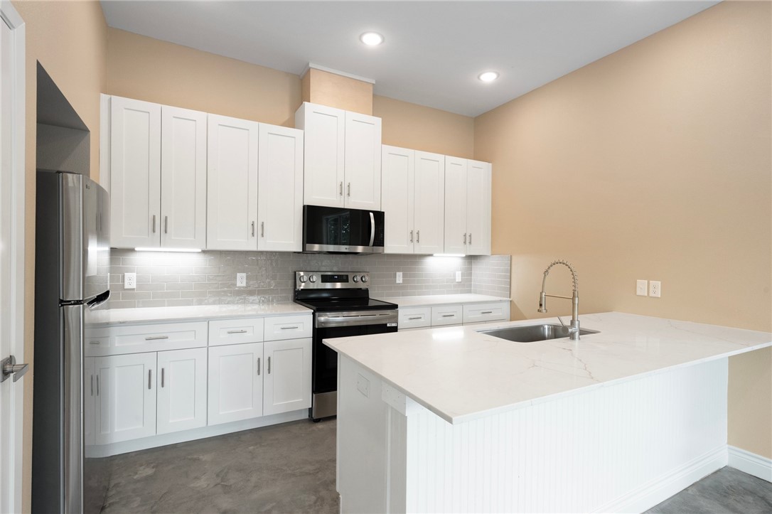 3213 Link Street, Unit 112 Bryan, TX 77801 - Photo 7 of 25 a kitchen with stainless steel appliances a sink a stove a microwave a sink a refrigerator with white cabinets