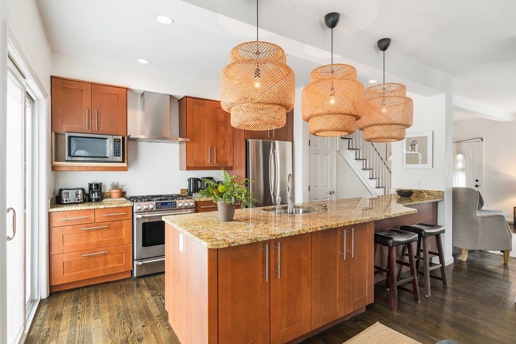 28 White Place Brookline, MA 02445 - Photo 6 of 18 a kitchen with stainless steel appliances granite countertop a stove a sink dishwasher and a dining table with wooden floor