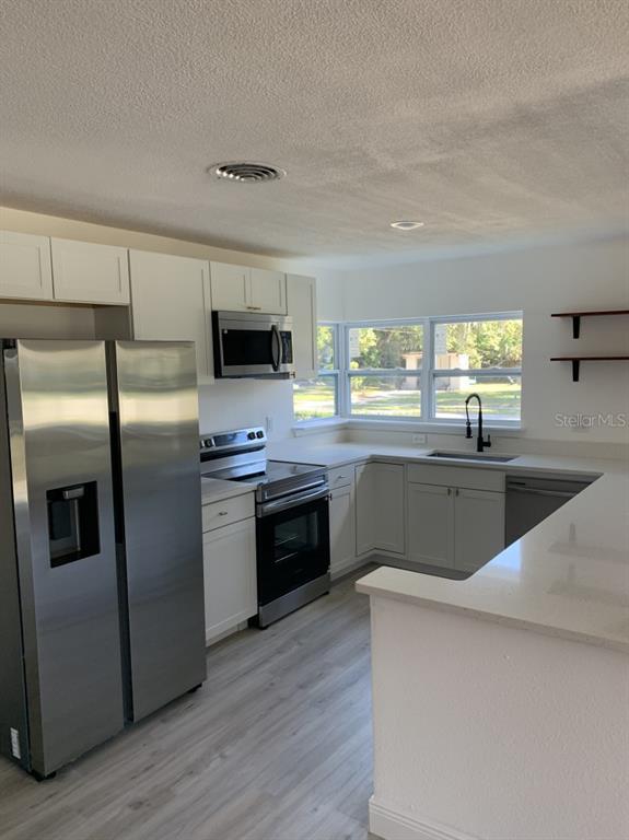 2237 Washington Road Mount Dora, FL 32757 - Photo 2 of 16 a kitchen with stainless steel appliances kitchen island granite countertop a stove a sink and a refrigerator