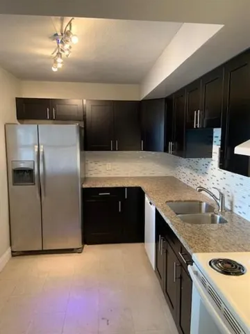 a kitchen with stainless steel appliances granite countertop a sink and a refrigerator