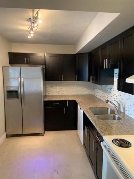4216 Inverrary Boulevard, Unit 92A Lauderhill, FL 33319 - Photo 2 of 11 a kitchen with stainless steel appliances granite countertop a sink and a refrigerator