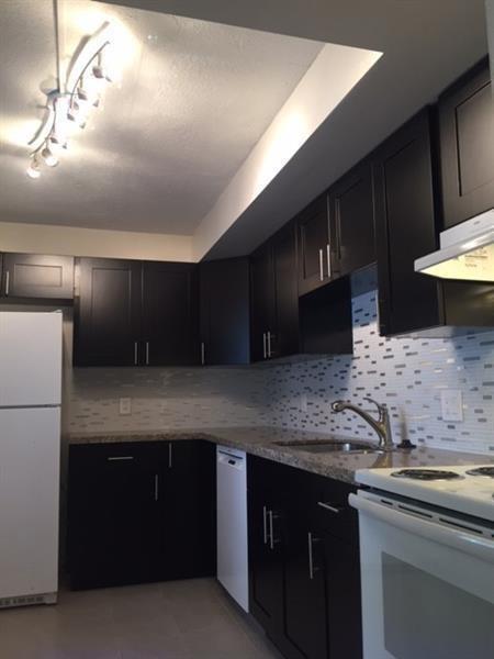 4216 Inverrary Boulevard, Unit 92A Lauderhill, FL 33319 - Photo 3 of 11 a kitchen with stainless steel appliances granite countertop a sink a stove and a refrigerator