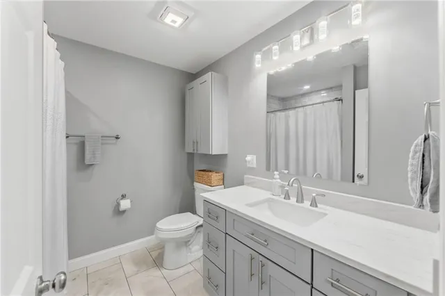 a bathroom with a granite countertop sink a toilet and a mirror