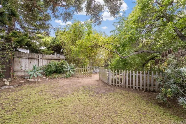 a view of a backyard with large trees and wooden fence