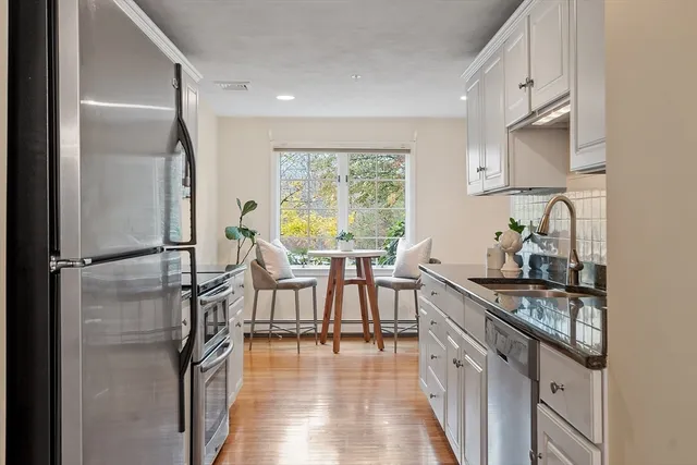 a kitchen with stainless steel appliances granite countertop a refrigerator a sink a stove and white cabinets