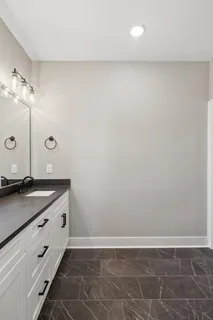 a bathroom with a granite countertop sink and white cabinets