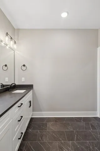 a bathroom with a granite countertop sink and white cabinets