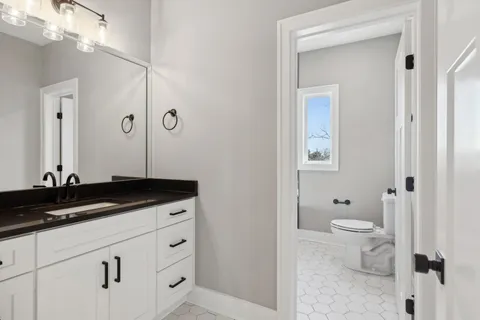 a bathroom with a granite countertop sink a toilet and a mirror