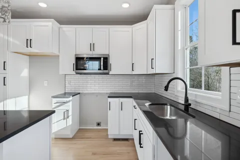a kitchen with granite countertop white cabinets and stainless steel appliances