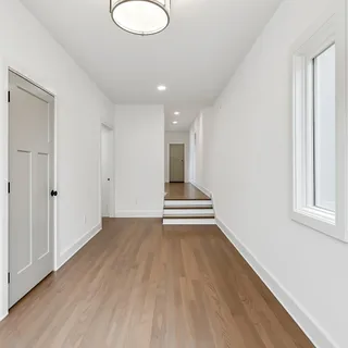 a view of an empty room with wooden floor and window
