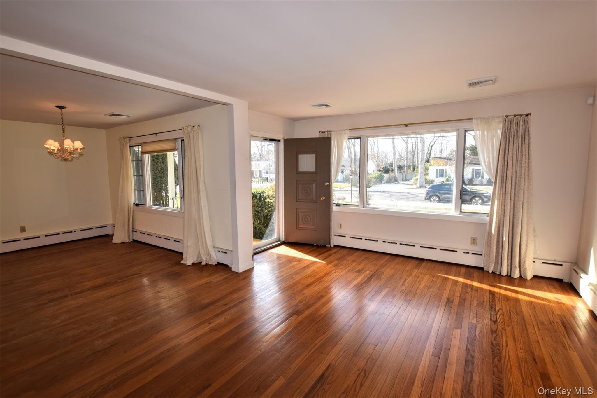 41 Country Club Road Bellport, NY 11713 - Photo 11 of 18 Foyer entrance featuring dark wood-style floors, a chandelier, and baseboard heating