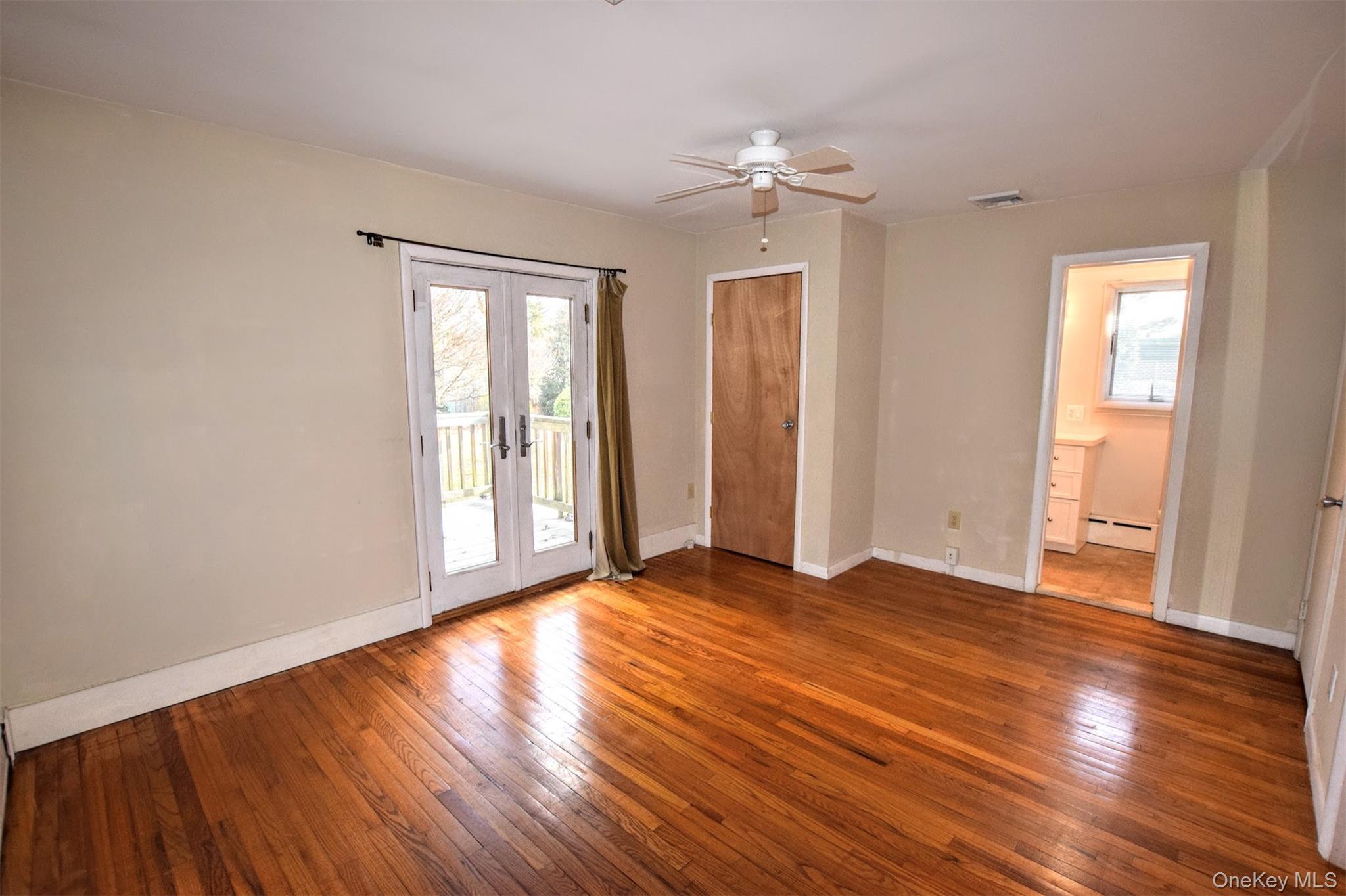 41 Country Club Road Bellport, NY 11713 - Photo 12 of 18 Empty room featuring french doors, hardwood / wood-style floors, a ceiling fan, and a baseboard radiator