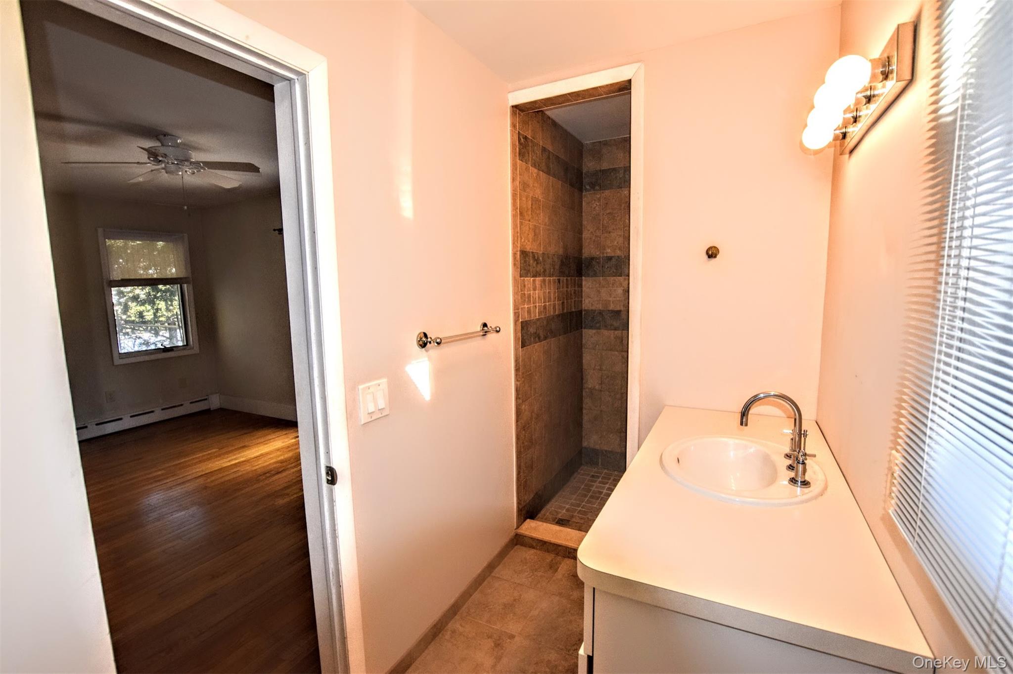 41 Country Club Road Bellport, NY 11713 - Photo 14 of 18 Full bathroom with a stall shower, vanity, a baseboard heating unit, and a ceiling fan