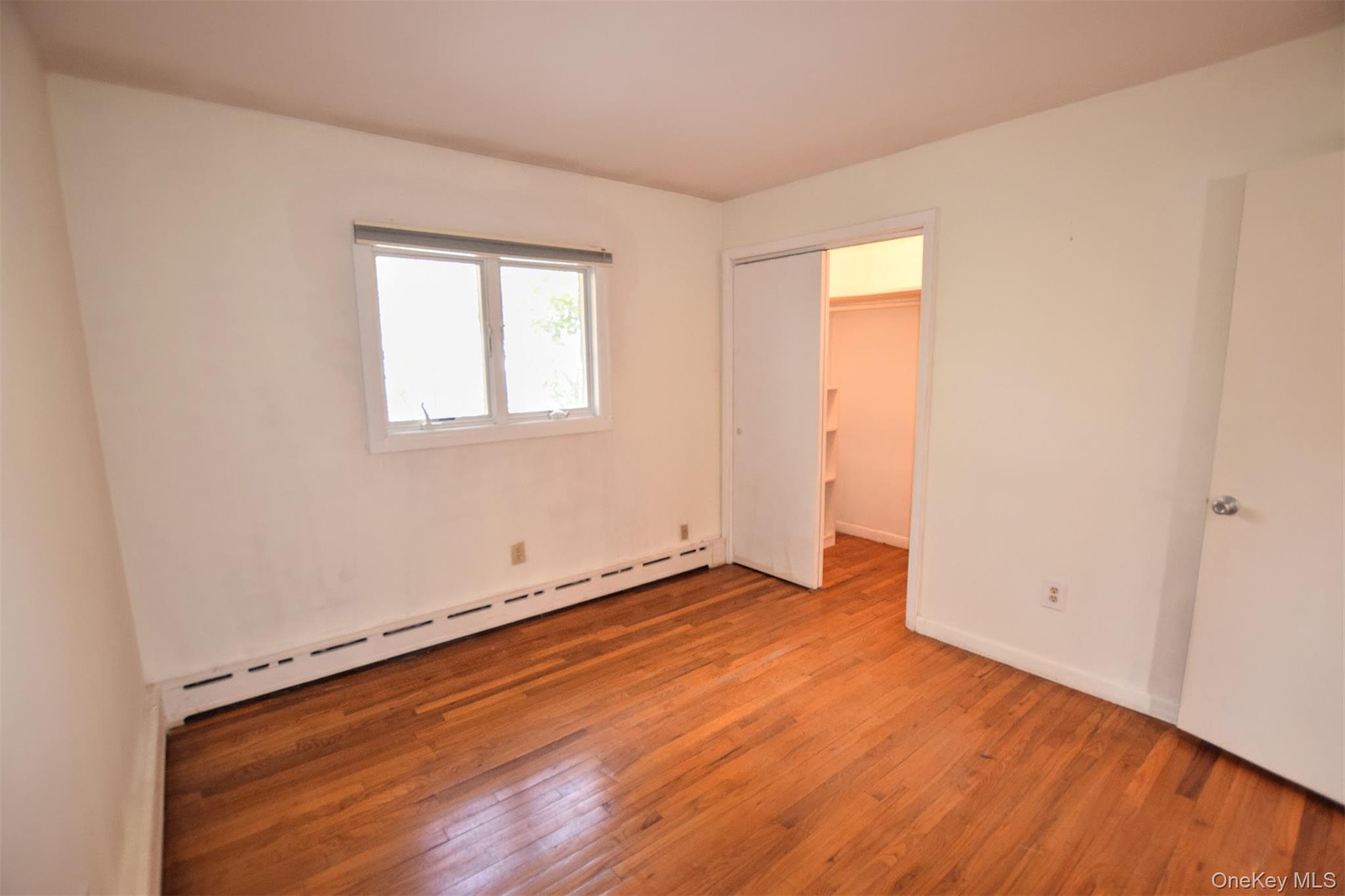 41 Country Club Road Bellport, NY 11713 - Photo 17 of 18 Unfurnished bedroom featuring baseboard heating and light wood-style flooring
