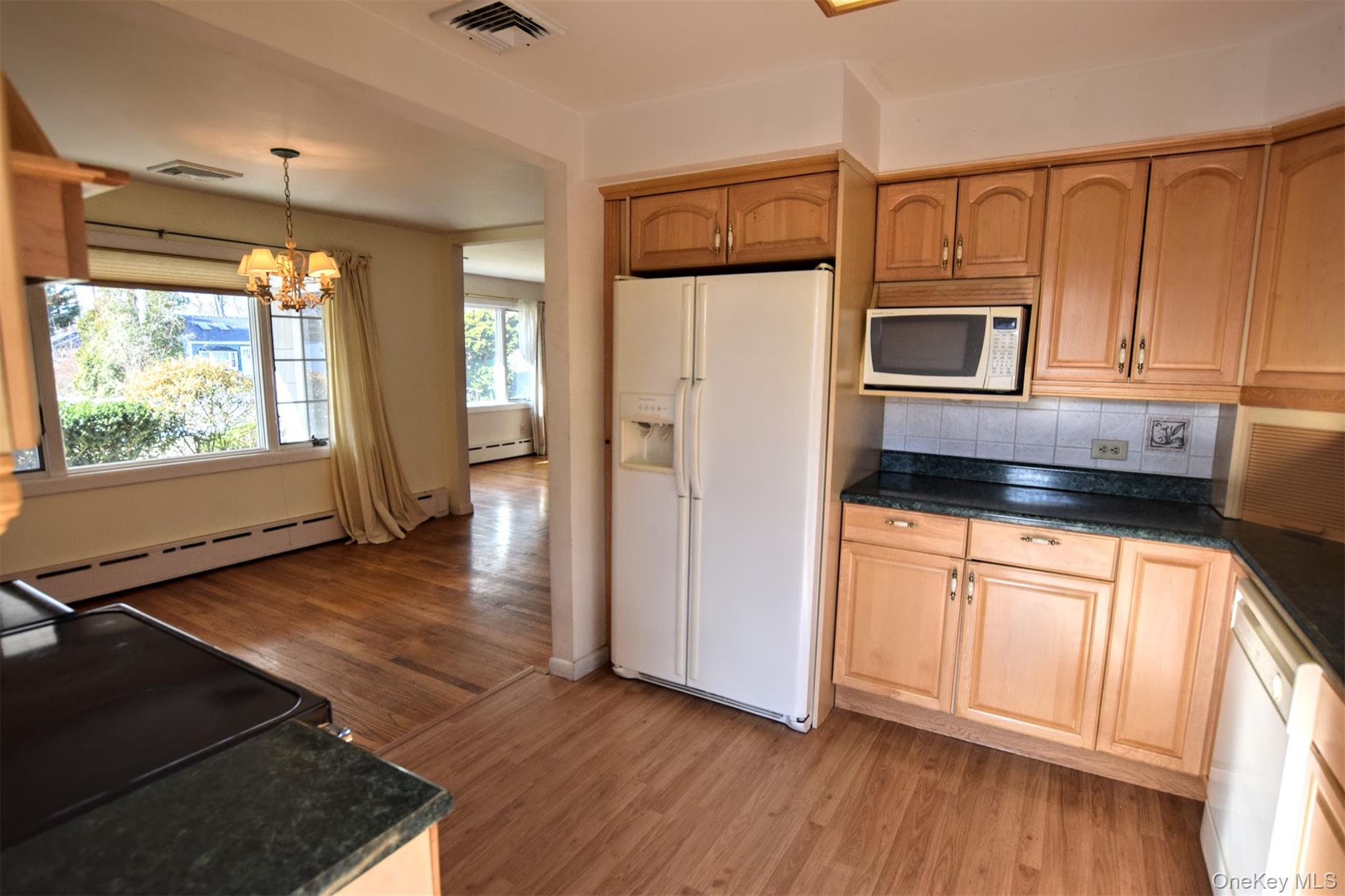 41 Country Club Road Bellport, NY 11713 - Photo 8 of 18 Kitchen with white appliances, a chandelier, light wood finished floors, hanging light fixtures, and tasteful backsplash