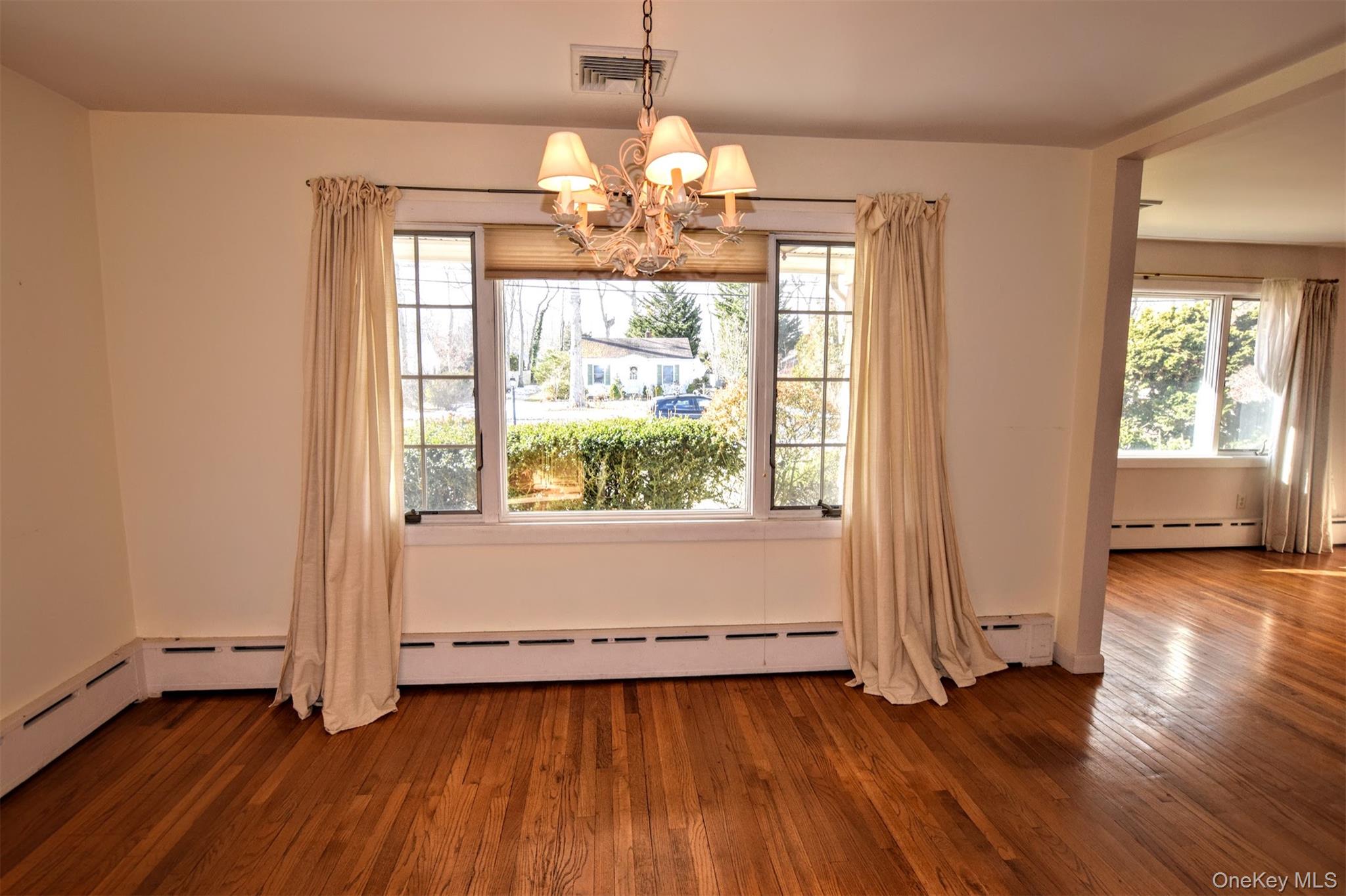 41 Country Club Road Bellport, NY 11713 - Photo 9 of 18 Unfurnished dining area with healthy amount of natural light, dark wood-style flooring, and a chandelier