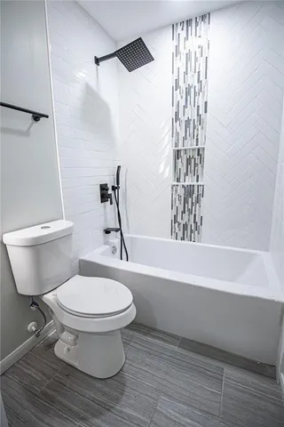 a white toilet sitting next to a bath tub and a shower