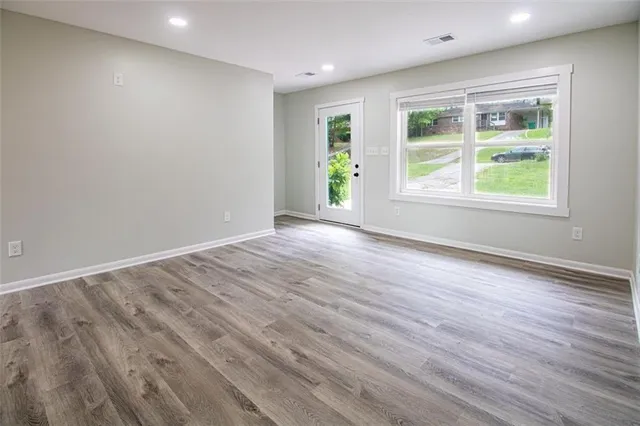 an empty room with wooden floor and windows