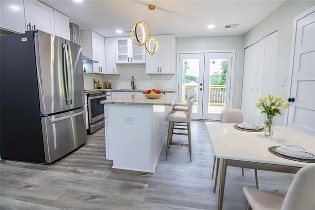a kitchen with stainless steel appliances a dining table chairs refrigerator and sink