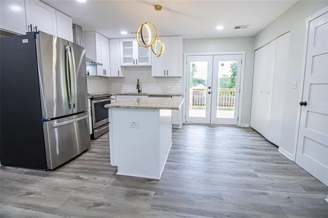 a kitchen with stainless steel appliances granite countertop a refrigerator a sink dishwasher a stove and a wooden floor