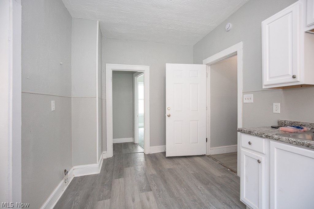 1000 Eddy Road Cleveland, OH 44108 - Photo 12 of 38 Kitchen featuring white cabinetry, light wood finished floors, a textured ceiling, and light stone counters
