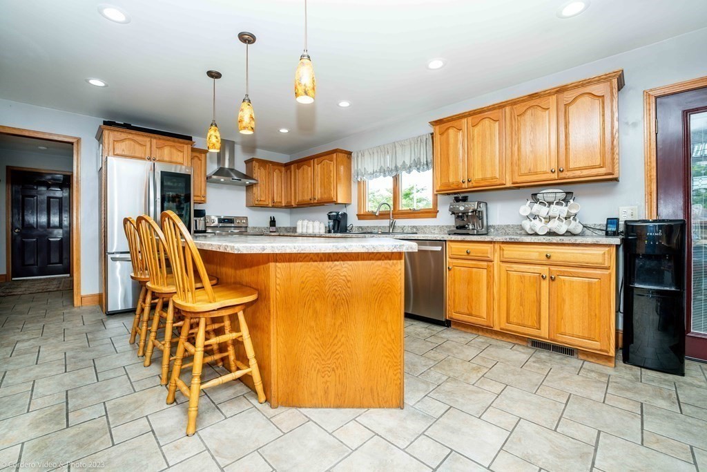 27 Peach Blossom Road Acushnet, MA 02743 - Photo 5 of 42 a kitchen with stainless steel appliances granite countertop a sink a stove a dining table and chairs