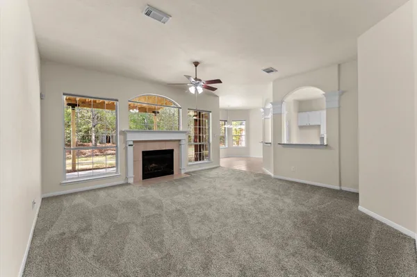 an empty room with a fireplace and a ceiling fan