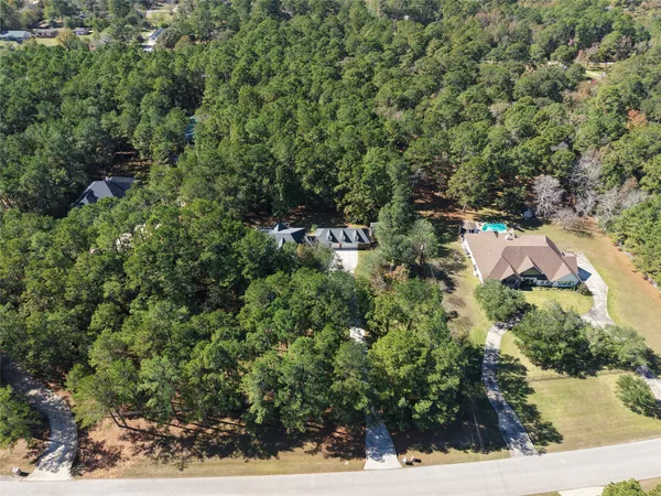 an aerial view of residential house with outdoor space and trees all around
