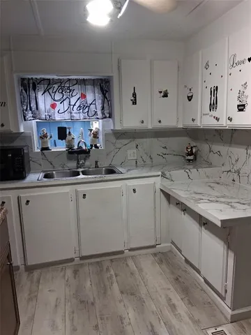a kitchen with a sink cabinets and wooden floor