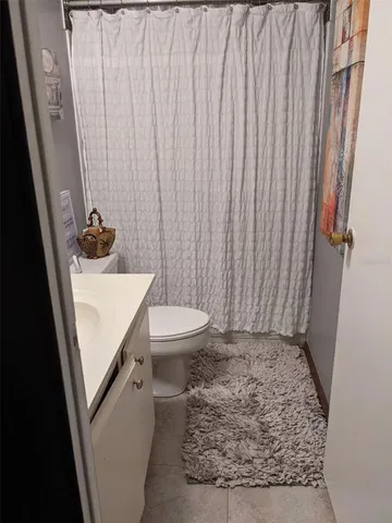 a bathroom with a sink a toilet and shower curtain