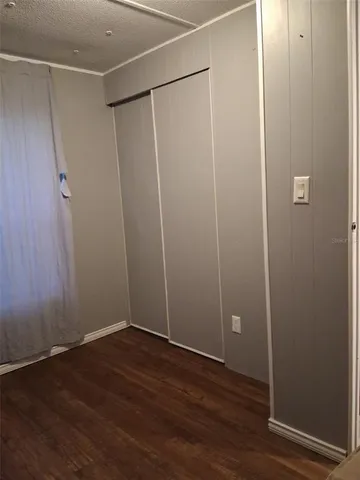 an empty room with wooden floor and fan
