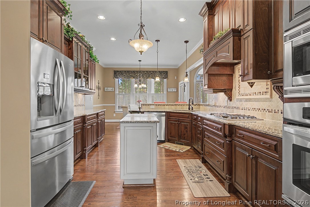 115 Micahs Way North Spring Lake, NC 28390 - Photo 19 of 39 a kitchen with stainless steel appliances granite countertop a refrigerator a sink dishwasher a stove and a dining table with wooden floor
