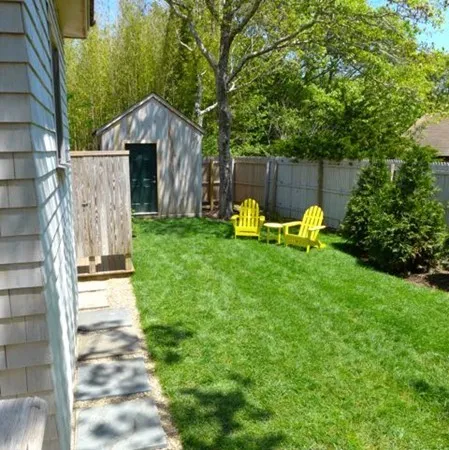 a view of a chair and table in the back yard of the house